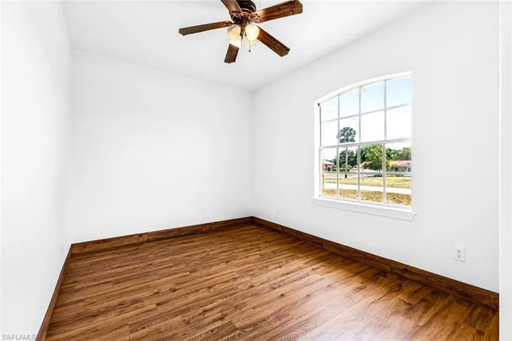 Spare room featuring wood finished floors, baseboards, and a ceiling fan