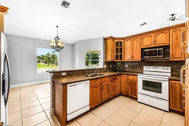 Kitchen with appliances with stainless steel finishes, a sink, brown cabinetry, and plenty of natural light