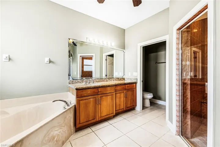 Full bathroom featuring a ceiling fan, toilet, a bath, tile patterned floors, and vanity