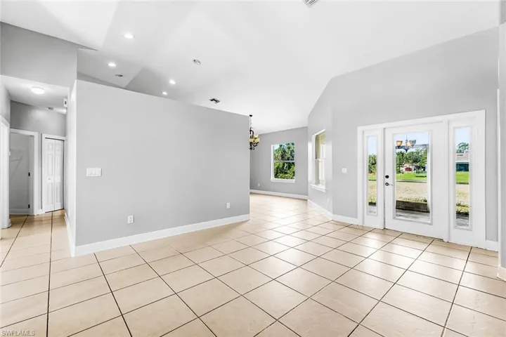 Unfurnished room featuring light tile patterned floors, a chandelier, baseboards, and recessed lighting