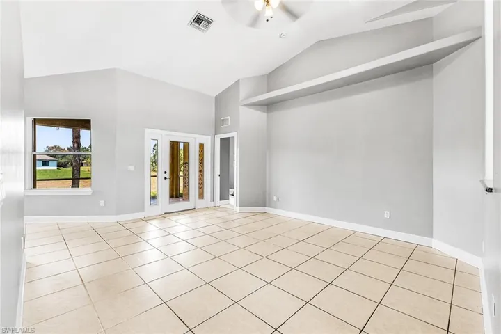 Tiled spare room with high vaulted ceiling, ceiling fan, and baseboards