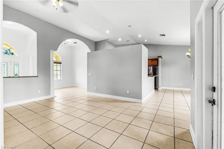 Spare room featuring light tile patterned flooring, a ceiling fan, vaulted ceiling, recessed lighting, and baseboards