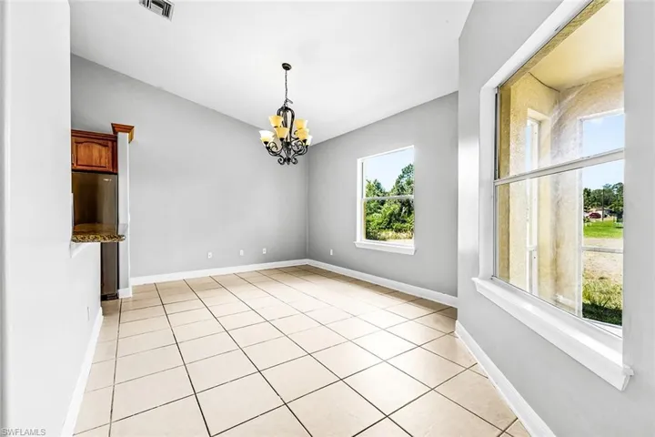 Unfurnished dining area featuring a chandelier, light tile patterned floors, and baseboards
