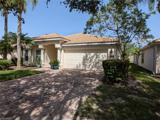 Mediterranean / spanish home featuring a tiled roof, stucco siding, an attached garage, and decorative driveway