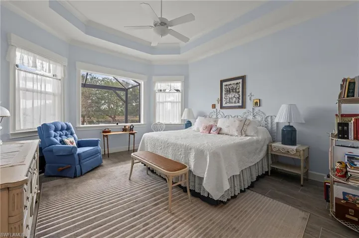 Bedroom with crown molding, dark hardwood / wood-style floors, a raised ceiling, and ceiling fan