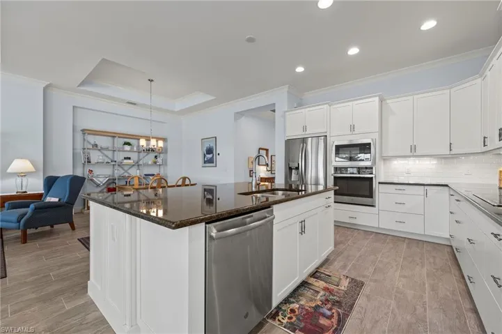 Kitchen with white cabinetry, appliances with stainless steel finishes, sink, and a center island with sink