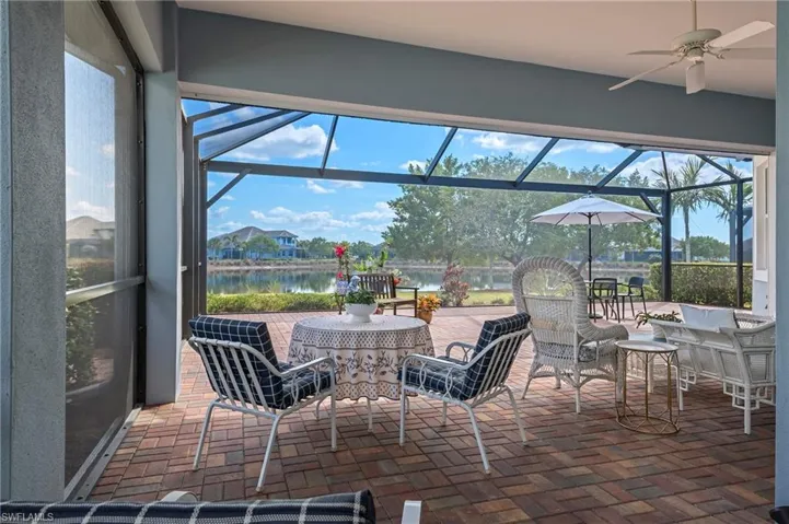 View of patio featuring ceiling fan, a water view, and glass enclosure