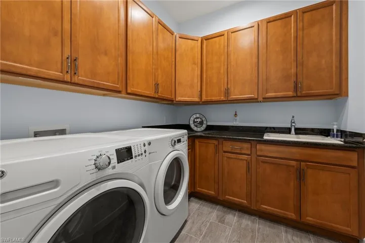 Laundry area with cabinets, separate washer and dryer, and sink
