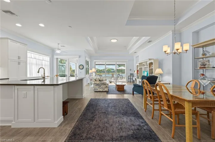 Dining space featuring crown molding, a raised ceiling, sink, and light hardwood / wood-style flooring
