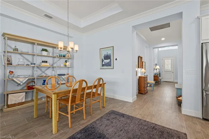 Dining area with ornamental molding, a raised ceiling, and a notable chandelier