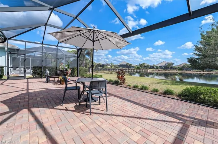 View of patio featuring a water view and glass enclosure