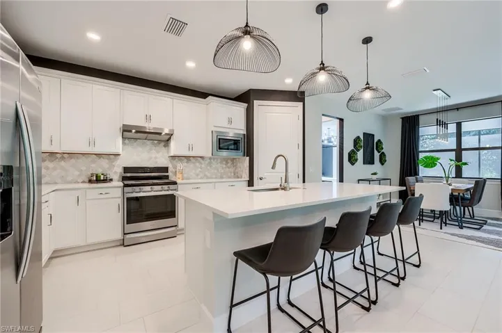 Kitchen featuring white cabinets, sink, stainless steel appliances, and a kitchen island with sink