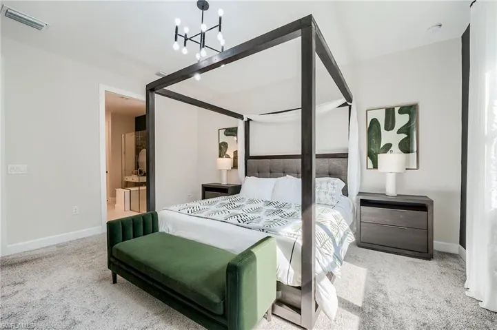 Bedroom with ensuite bath, carpet, and a chandelier