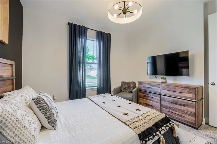 Carpeted bedroom with multiple windows and an inviting chandelier