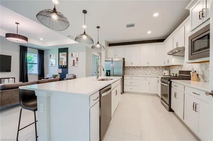 Kitchen with white cabinetry, a center island with sink, and appliances with stainless steel finishes