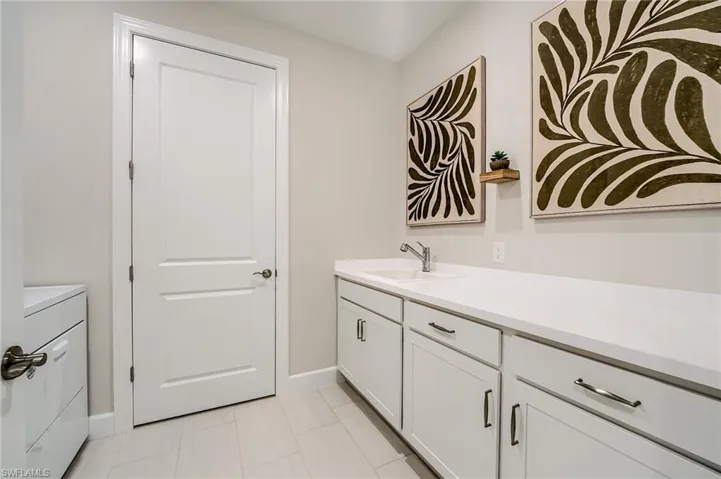 Bathroom with tile patterned flooring, vanity, and washer / dryer