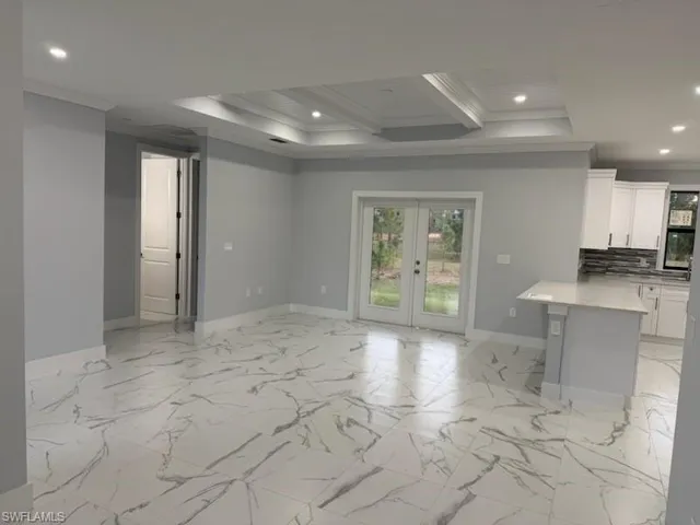 Kitchen featuring decorative backsplash, french doors, ornamental molding, beamed ceiling, and white cabinetry