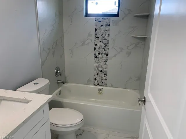 Full bathroom featuring vanity, toilet, and tiled shower / bath combo