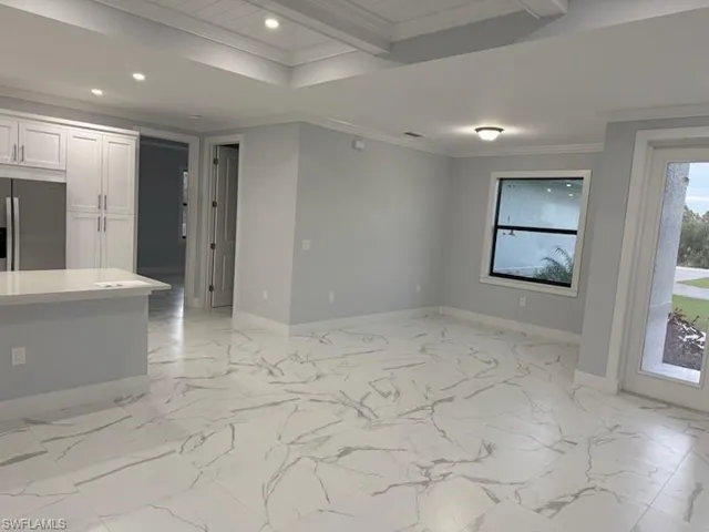 Empty room with crown molding and beamed ceiling