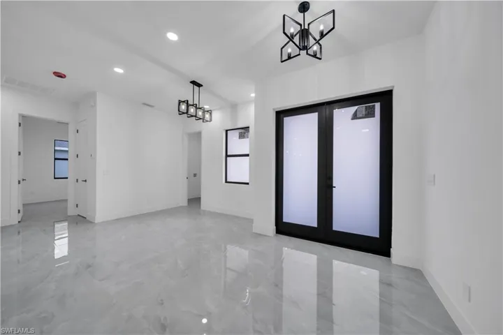 Entrance foyer with a chandelier, recessed lighting, light marble finish floors, and french doors