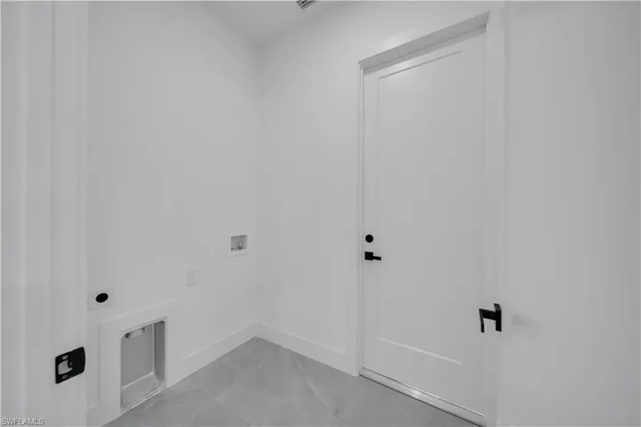 Washroom with electric dryer hookup, hookup for a washing machine, and light marble finish floors