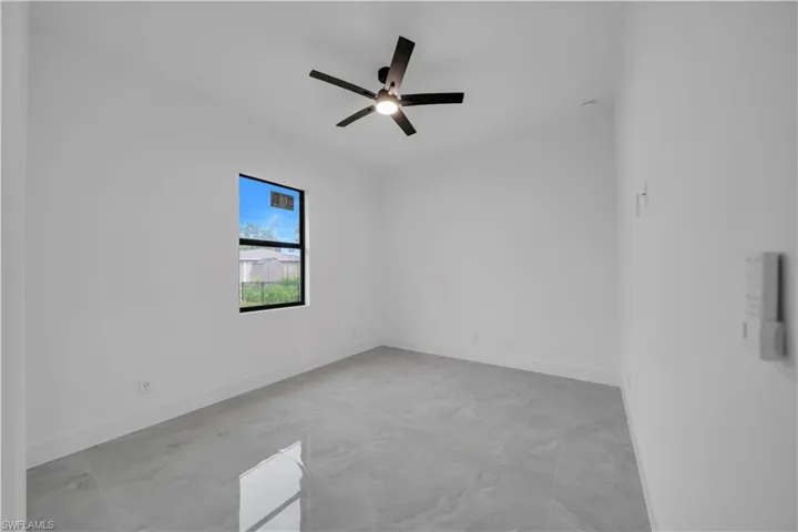 Spare room featuring a ceiling fan and baseboards