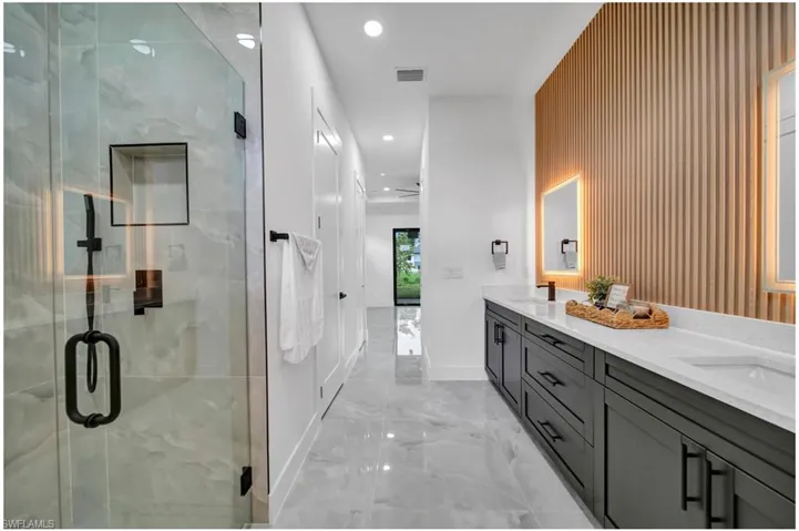 Bathroom featuring marble tiled floors, double vanity, a stall shower, and recessed lighting