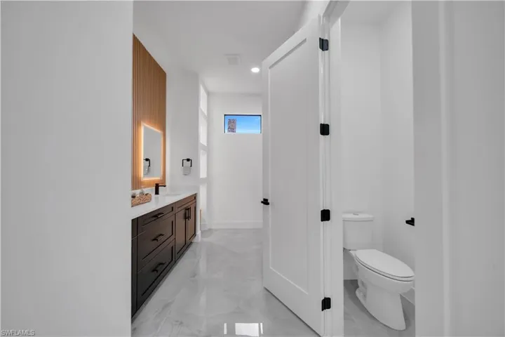 Bathroom featuring marble look tiles, vanity, and recessed lighting