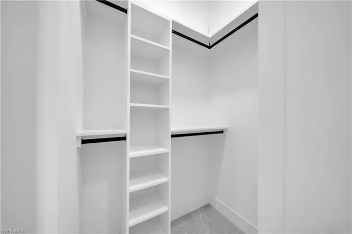 Spacious closet featuring light marble finish floors