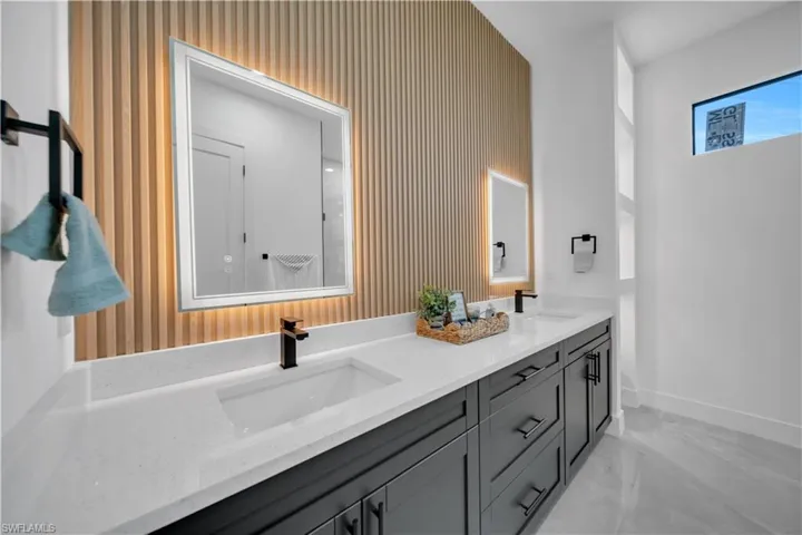 Bathroom featuring double vanity, wallpapered walls, and marble finish floors