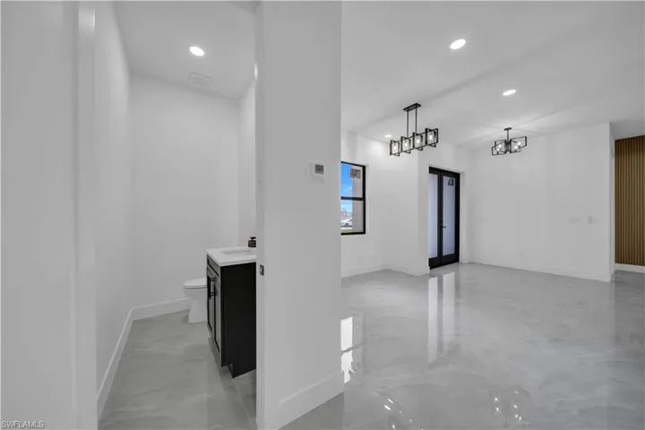 Hall with recessed lighting, light marble finish flooring, and a chandelier