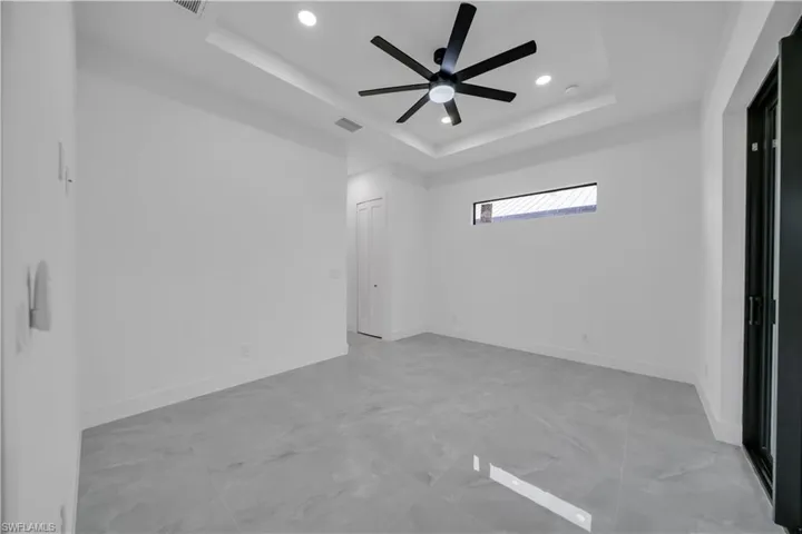 Empty room featuring a raised ceiling, a ceiling fan, and recessed lighting
