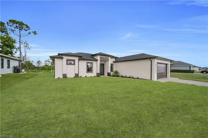 Prairie-style house with concrete driveway, a front lawn, stucco siding, and a garage