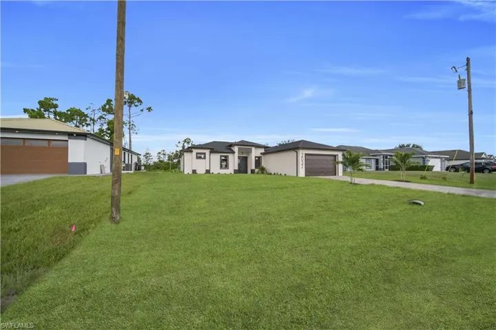 View of front of home with concrete driveway, a front yard, and a garage