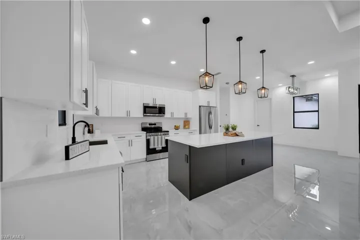 Kitchen with stainless steel appliances, light marble finish floors, a center island, white cabinetry, and recessed lighting