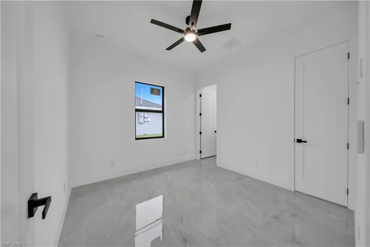 Unfurnished bedroom featuring a ceiling fan and light marble finish floors
