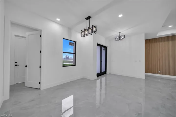 Unfurnished room with light marble finish flooring, recessed lighting, a chandelier, and wood walls