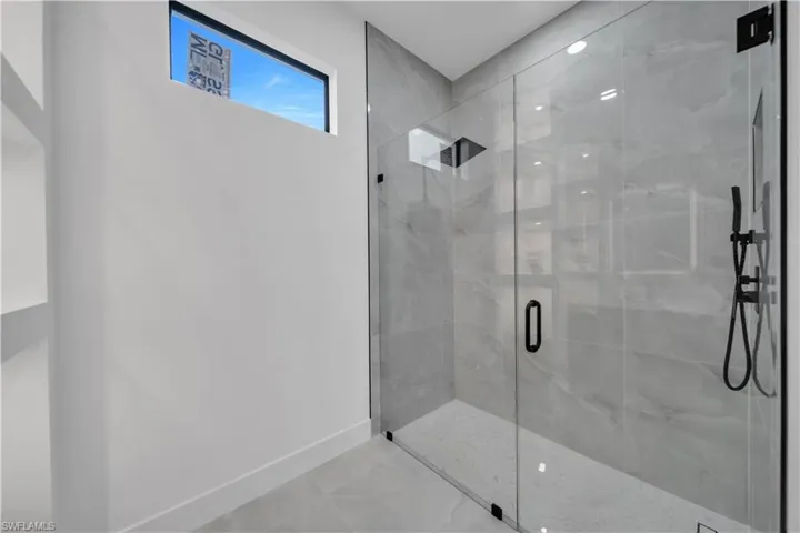 Full bath featuring a marble finish shower and baseboards