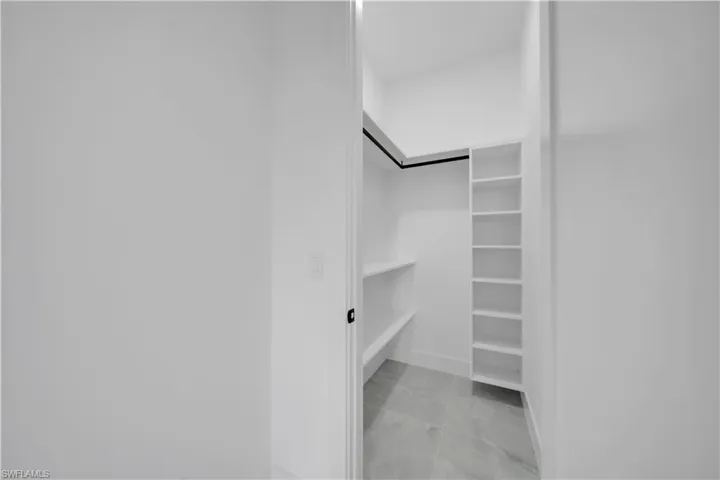 Walk in closet featuring light marble finish flooring