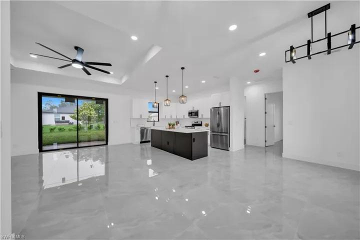 Kitchen with appliances with stainless steel finishes, open floor plan, a center island, light countertops, and recessed lighting