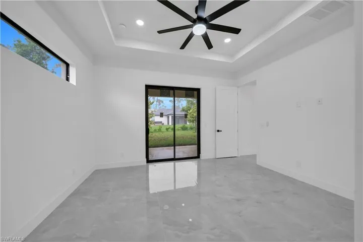 Empty room with plenty of natural light, ceiling fan, a raised ceiling, recessed lighting, and light marble finish floors