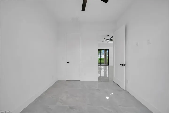Unfurnished room with ceiling fan and light marble finish floors