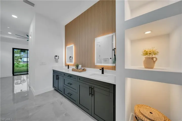 Bathroom with marble finish flooring, double vanity, and recessed lighting