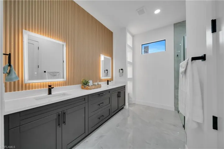 Full bath with double vanity, a shower with door, and marble finish flooring