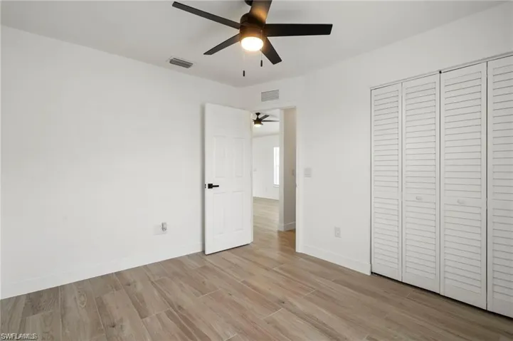 Unfurnished bedroom with light wood-type flooring, ceiling fan, and a closet