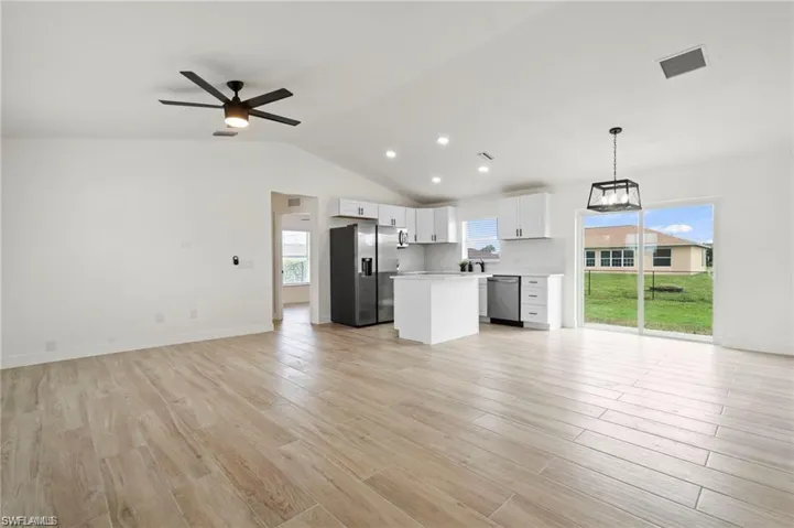 Kitchen featuring light wood-type flooring, white cabinetry, stainless steel appliances, ceiling fan, and hanging light fixtures