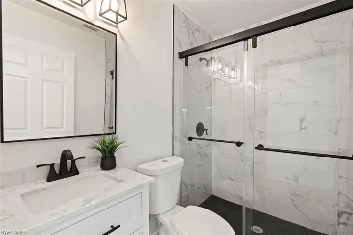 Bathroom with toilet, a shower with door, and vanity