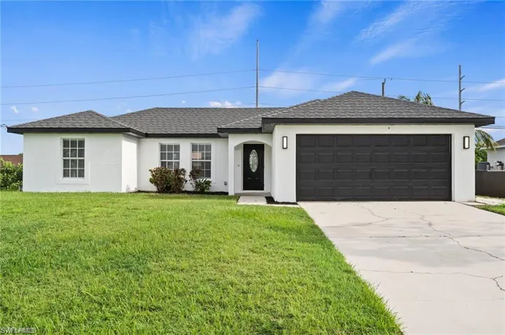 Ranch-style house featuring a front lawn and a garage