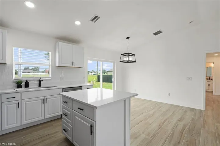Kitchen with a healthy amount of sunlight, white cabinetry, and a kitchen island