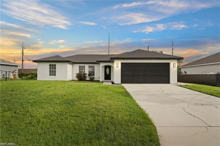 Ranch-style home featuring a lawn and a garage